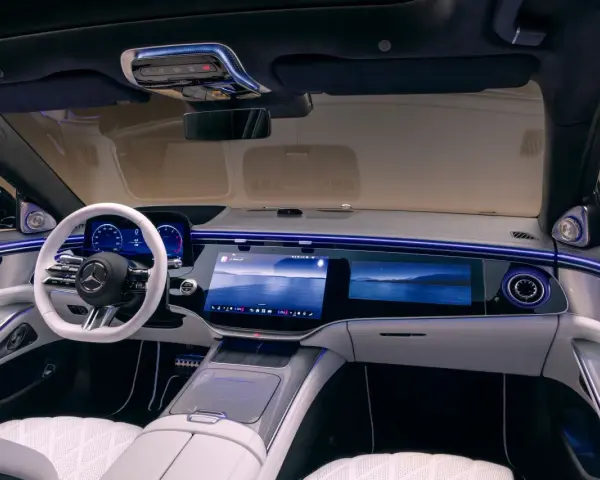 Luxuriöses Auto-Armaturenbrett mit großem Touchscreen, weißem Lenkrad und Ambientebeleuchtung.