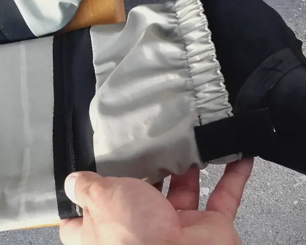 Hand hält ein Hosenbein mit elastischem Bund und Klettverschluss. Vielleicht ein Flicken für die wathose?