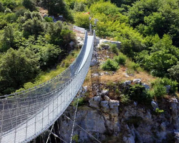 Un lungo ponte tibetano si snoda tra rocce e vegetazione lussureggiante, offrendo un'avventura mozzafiato nei dintorni di Salerno.