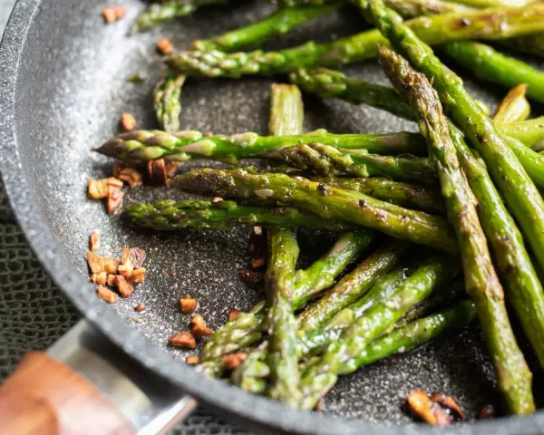 Asparagi in padella, croccanti e saporiti, con pezzetti di pancetta tostata che aggiungono un tocco in più.