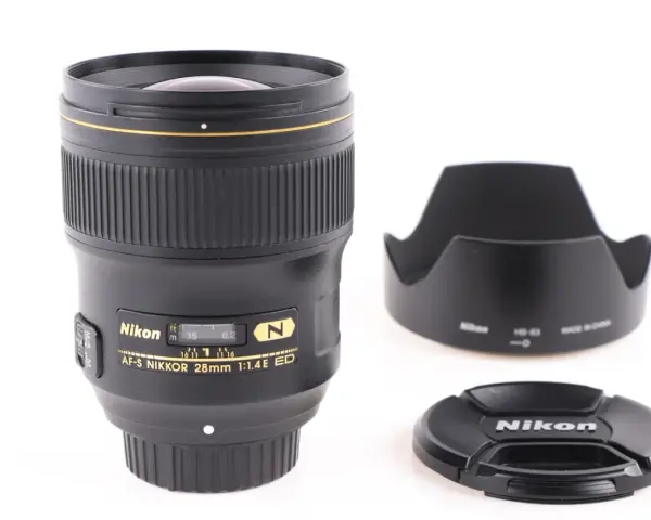 Obiektyw AF-S NIKKOR 28mm 1:1.4E ED z osłoną przeciwsłoneczną i deklem. Jasne oznaczenia obiektywów Nikon.