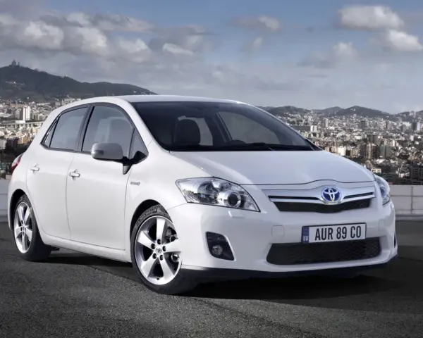 Biała Toyota Auris hybryda na tle miasta. Czy warto zainwestować w ten model?