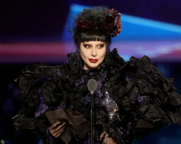 Lady Gaga w Polsce, w czarnej, falbaniastej sukni z fioletowymi wstawkami, odbiera nagrodę.
