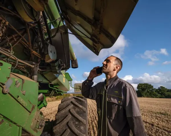 Rolnik rozmawia przez telefon, sprawdzając **waryński części** kombajnu.