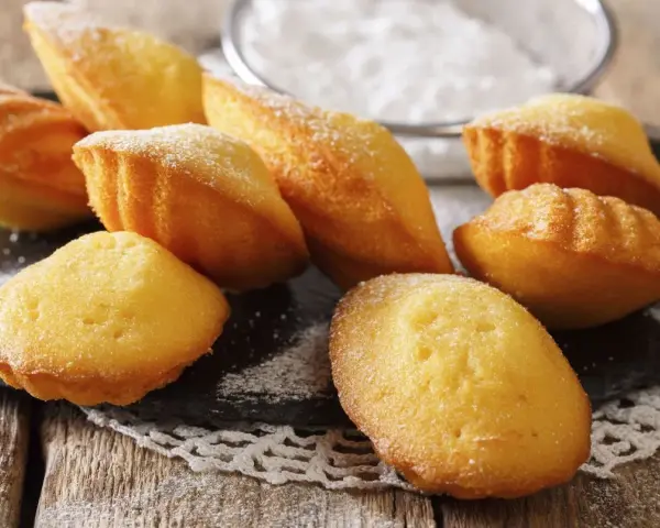 Des madeleines dorées, saupoudrées de sucre glace, prêtes à être dégustées. Une invitation à la recette madeleine parfaite.