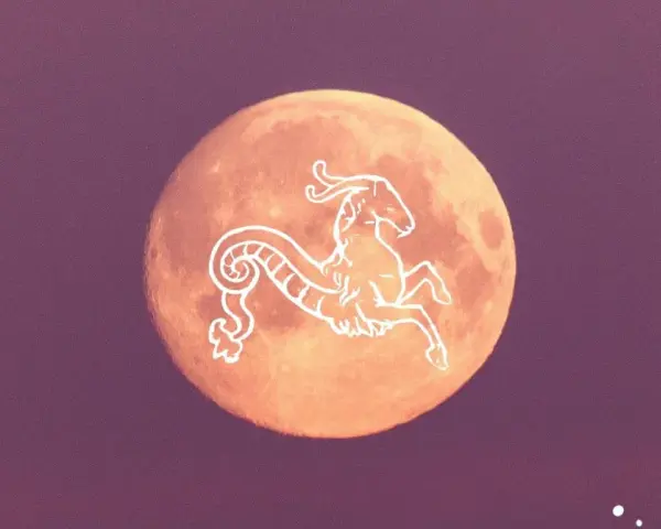 Pomarańczowy księżyc w Koziorożcu, ozdobiony białym symbolem zodiaku.