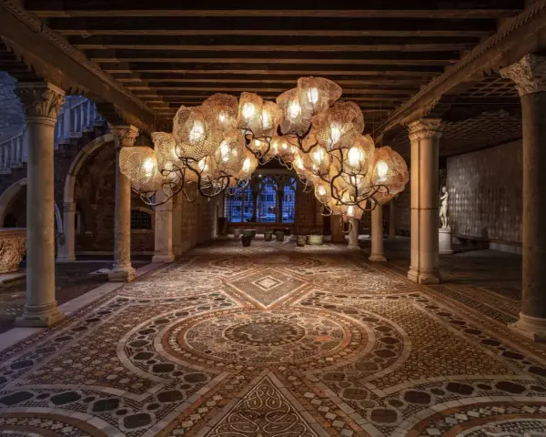 Interni Ca' d'Oro: un lampadario scenografico illumina il cortile con pavimenti a mosaico e colonne antiche.