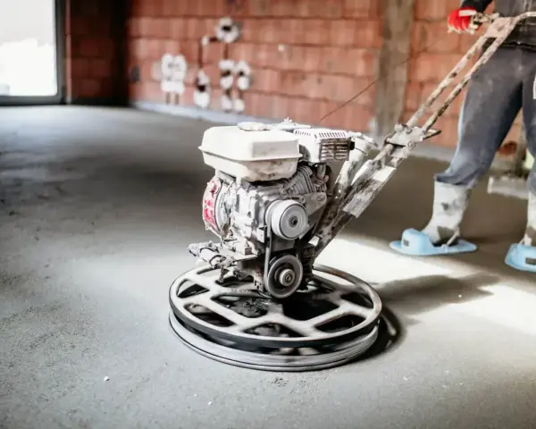 Pracownik wygładza wylewkę styrobetonową za pomocą mechanicznej zacieraczki. Sprawdź aktualną wylewka styrobeton cena za m2.