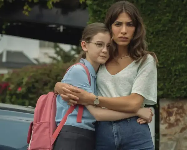 Erin Carter abbraccia una bambina con uno zaino rosa. La donna sembra preoccupata, la bambina protetta.