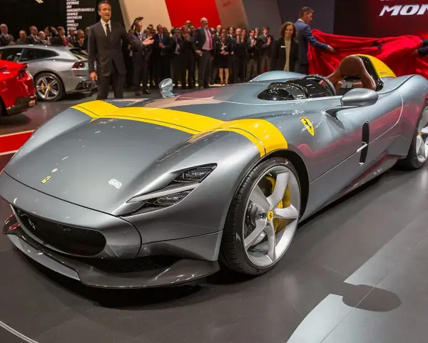 Szary Ferrari Monza SP1 z żółtymi pasami, odsłaniany na scenie.