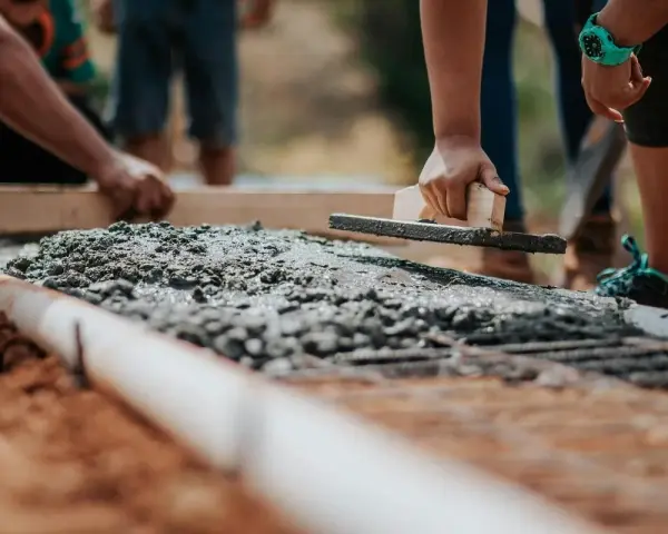 Pracownicy wyrównują świeży beton na fundamencie. Jaki beton na fundament b20 czy b25?