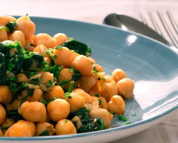 Garbanzos salteados con espinacas y ajo, una de las muchas recetas con garbanzos de bote, servidos en plato azul.