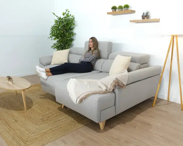 Mujer relajada en un sofá en medio del salón, con una manta y cojines.