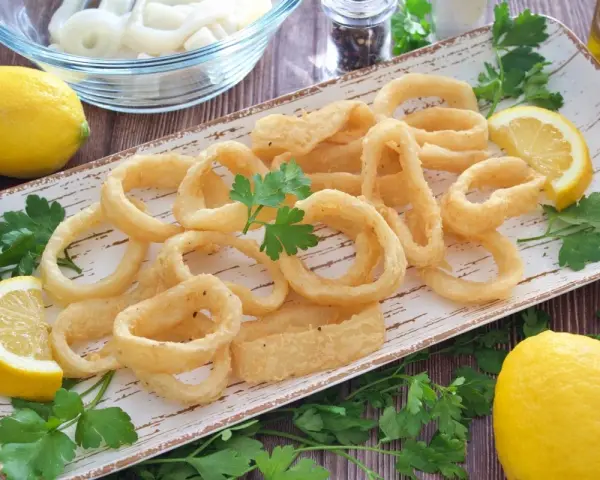 Calamares a la andaluza crujientes y dorados, servidos con limones frescos y perejil.