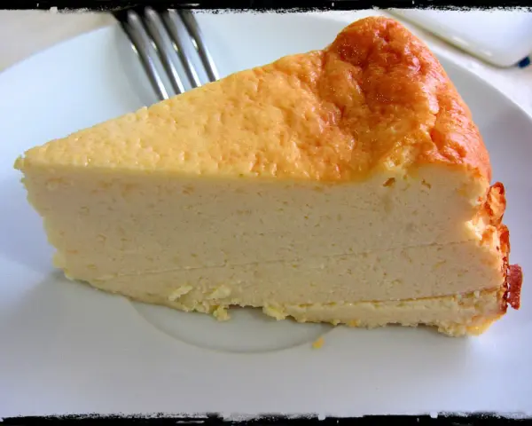 Una rebanada de tarta de queso light, con su dorada superficie y cremosa textura, lista para disfrutar.