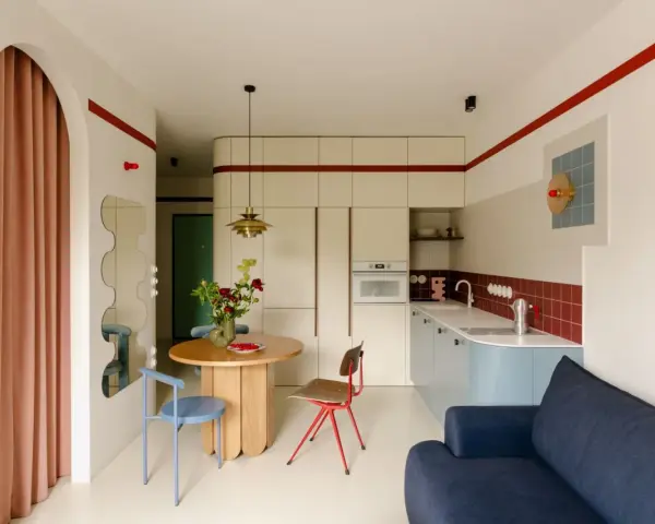 Un angolo di casa moderna con richiami alle case tipiche italiane: un tavolo rotondo, sedie colorate e una cucina funzionale.
