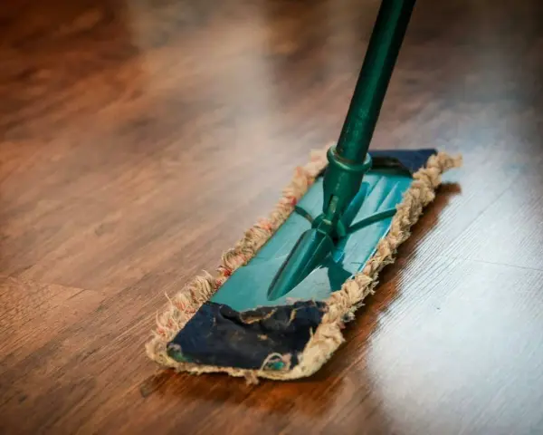 Mopa limpiando un suelo de parquet. Descubre remedios caseros para reparar parquet y mantenerlo como nuevo.