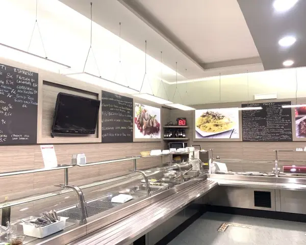 Interior of a restaurant with a display counter, menu boards, and food images.
