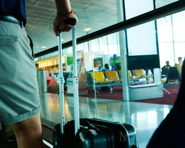 Osoba z walizką czeka na lotnisku. Wymiary bagażu rejestrowanego są kluczowe dla komfortowej podróży.
