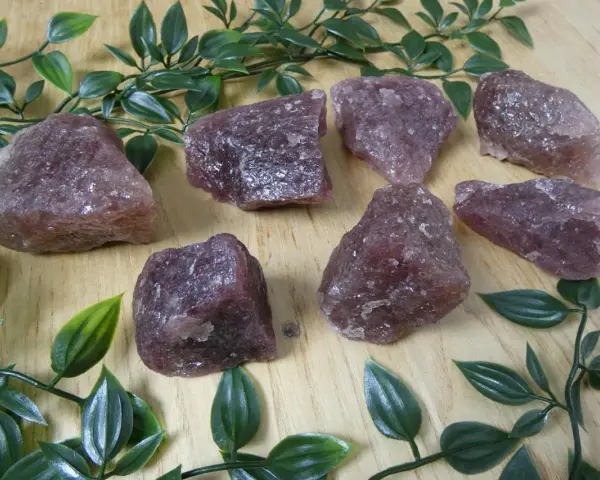 Gruppo di quarzo fragola grezzo su fondo di legno. Le sue proprietà sono note per favorire l'amore e la guarigione emotiva.