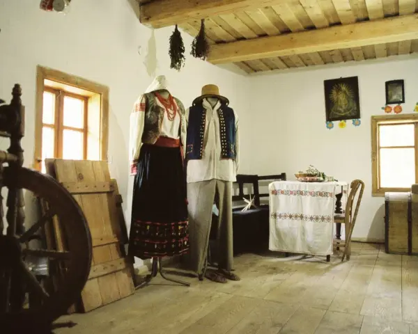 Tradycyjne stroje ludowe, kołowrotek i obrazy religijne tworzą klimat dawnej wsi. To żywa hel historia.