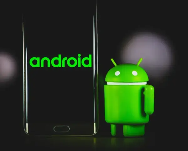 Zielony robot Android obok telefonu z logo Android 13.