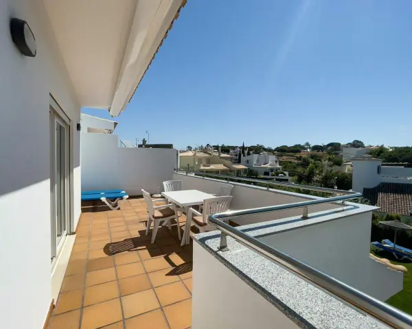 Słoneczny balkon z meblami i widokiem na domki. Idealne miejsce na poranną kawę i planowanie dnia.