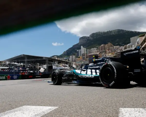Coche de clasificación F1 en Mónaco, con el mar y edificios de lujo de fondo.