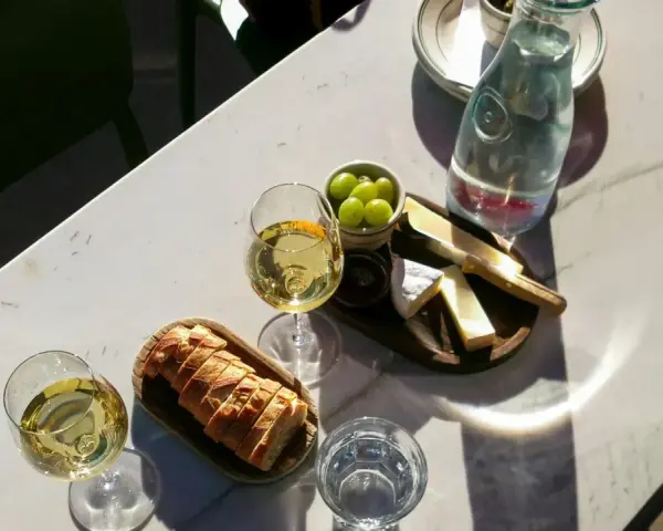 Dwa kieliszki orzeźwiającego gruner veltliner wino, chrupiąca bagietka, ser i winogrona na marmurowym stole.