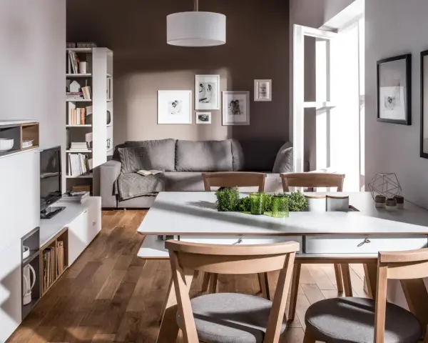 Nowoczesny salon z szarą kanapą i drewnianymi krzesłami. Czy brązowy pasuje do szarego? Tak, w tej aranżacji tworzy przytulną atmosferę.