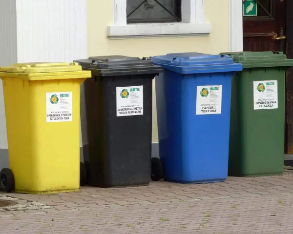 Cztery kosze na śmieci: żółty (plastik), czarny (metal), niebieski (papier) i zielony (szkło). BDO 150102 to kod odpadu dla opakowań z tworzyw sztucznych.