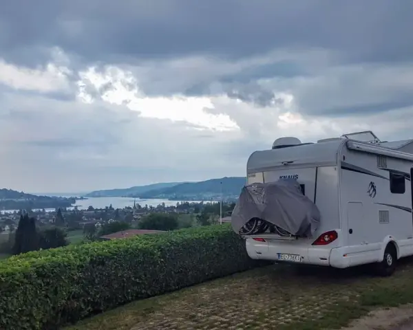 Kamper zaparkowany na kempingu w Czeskiej Szwajcarii, z widokiem na jezioro i wzgórza.