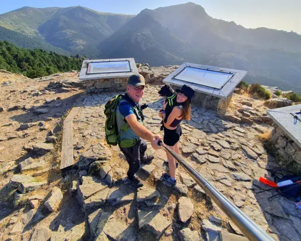 Pareja y perro posan en la barranca mirador de las canchas, disfrutando de las vistas montañosas.