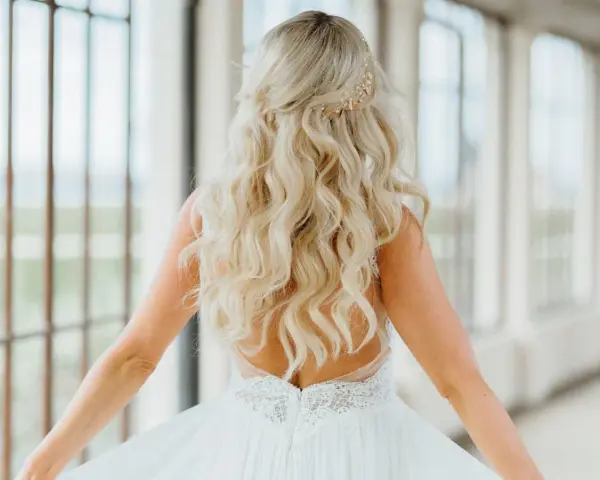Długie, falowane blond włosy ozdobione złotą spinką. Fryzura w stylu lat 20. idealna na ślub.