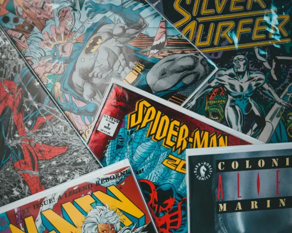 Stos komiksów z postaciami takimi jak Spider-Man, Batman i Silver Surfer. Czy komiks to książka? To zależy od tego, jak na to spojrzeć!