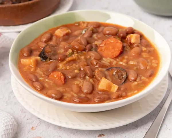 Un tazón de judías pintas con chorizo, patatas y arroz en un guiso meloso.