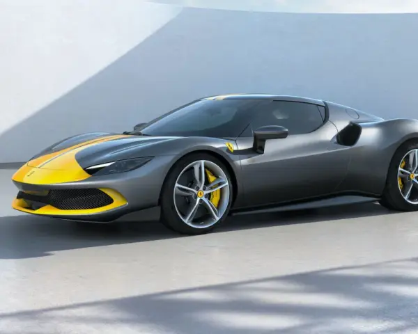 Szary Ferrari 296 GTB z żółtymi pasami na masce i dachu, stojący na betonowej posadzce.