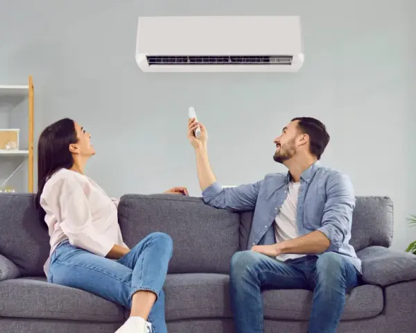 Pareja ajustando el aire acondicionado para encontrar la temperatura ideal y ahorrar energía.