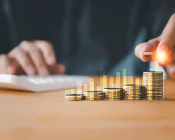 Main qui ajoute une pièce à une pile, symbolisant la croissance de la rémunération variable dans le respect du code du travail.