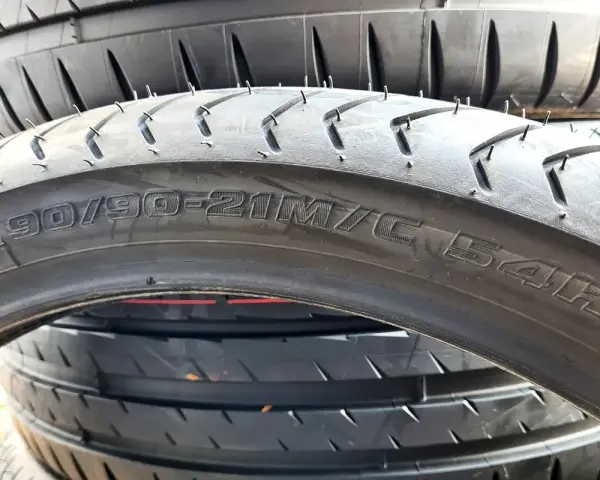 Profil opony 90/90-21M/C 54H. Widok z bliska na bieżnik i oznaczenia rozmiaru opony motocyklowej.