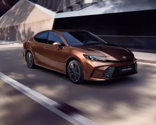 Brązowa Toyota Camry Hybrid w ruchu. Sprawdź aktualną toyota camry cena i wybierz swój wymarzony model.