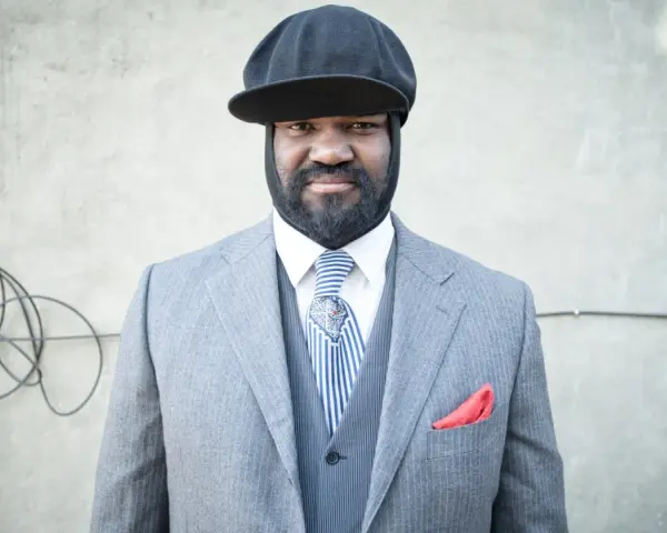 Gregory Porter w eleganckim garniturze i czapce, gotowy na koncert.