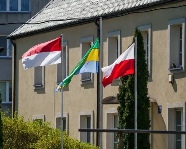 Trzy flagi powiewają przed budynkiem: biało-czerwona flaga Polski, flaga Monako (identyczna jak Indonezji) i flaga Gabonu.