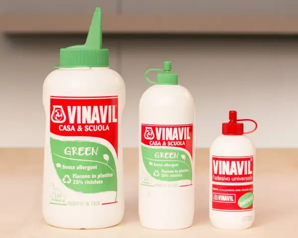 Tre flaconi di colla Vinavil, un adesivo universale pva glue cos'è, in diverse misure, con tappi verdi e rossi.