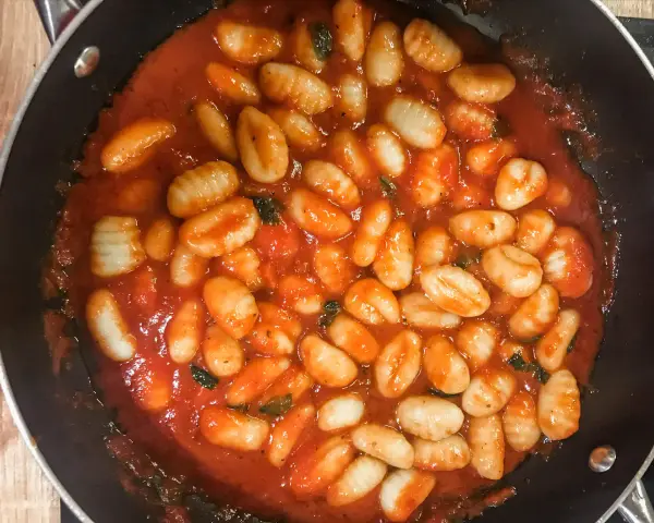 Pyszne gnocchi w aromatycznym sosie pomidorowym z ziołami, gotowe do podania. Idealny sos do gnocchi na szybki obiad.