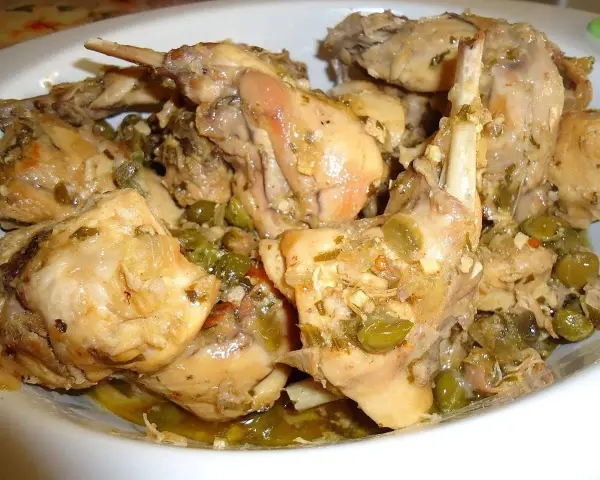 Piatto fumante di coniglio alla cacciatora in bianco, con olive verdi e erbe aromatiche. Un classico della cucina italiana.