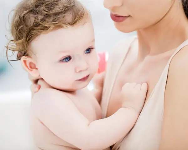 Ein Baby mit blauen Augen und zerzaustem Haar wird von seiner Mutter gehalten. Es ist fast 46 Wochen alt und durchläuft einen Entwicklungsschub.