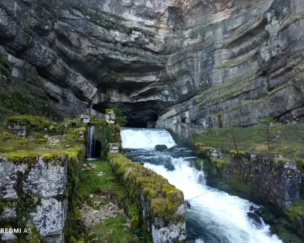 La source de la Loue, un spectacle naturel impressionnant. L'itinéraire mène à travers ce paysage rocheux où l'eau jaillit d'une grotte.