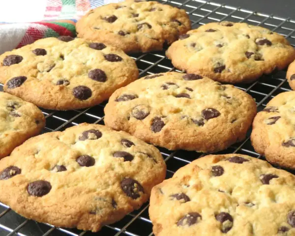 Un montón de galletas con pepitas de chocolate recién horneadas, doradas y deliciosas, enfriándose en una rejilla.