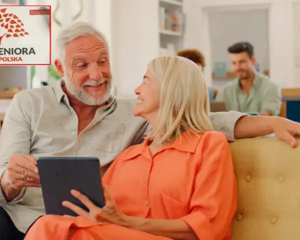 Uśmiechnięci seniorzy przeglądają tablet, obok nich logo "Karta Seniora Ogólnopolska".